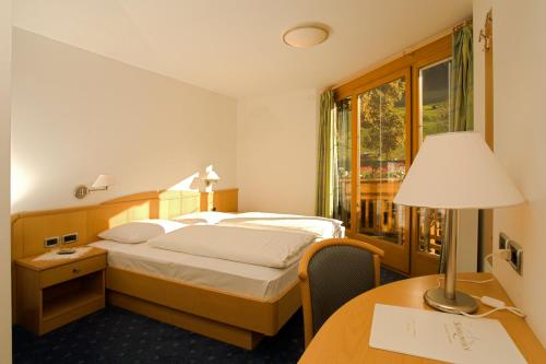 拉辛Hotel Schölzhorn Superior的酒店客房配有一张床和一张带台灯的书桌