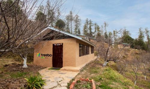 西姆拉Treebo Trend Daak Bangla Retreat With Mountain View的森林中有一扇门的小建筑