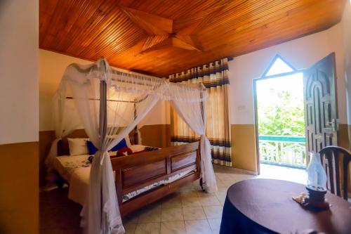 锡吉里亚The Green Heaven Resort的一间卧室设有天蓬床和窗户。