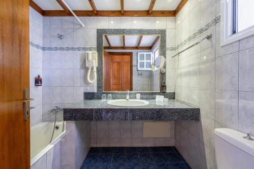 马尔马里Palladium hotel的一间带水槽、浴缸和镜子的浴室