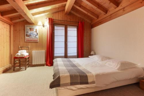 夏蒙尼-勃朗峰Chalet Ancelles - Les Praz - Golf - Vue Mont-Blanc - Randonnées的一间卧室配有一张带红色窗帘的床和一扇窗户