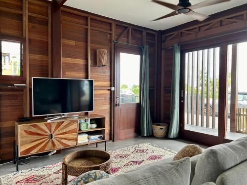 圣皮埃尔Kaz C2C - Une maison Balinaise avec jacuzzi的客厅设有木墙和平面电视。