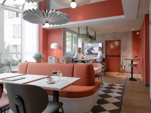 吕埃尔-马尔迈松马尔马逊巴黎吕埃宜必思酒店的餐厅设有橙色椅子和酒杯桌子