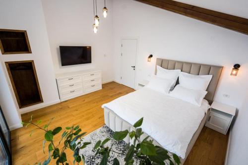 锡纳亚Stone House Sinaia的一间卧室配有一张带白色床单的床和一台电视。