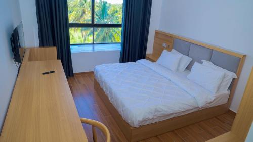 达累斯萨拉姆PALM VILLAGE BUSINESS HOTEL的一间卧室配有一张带书桌的床和窗户。