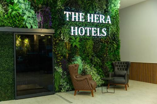 伊斯坦布尔The Hera Business Hotels & Spa的绿色的墙,带两把椅子和酒店标志