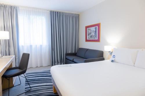 沃尔斯雷诺富特曼切斯特西区酒店的酒店客房设有一张大床和一张沙发。