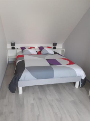 La MilesseHébergement individuel chez particulier proche 24h du Mans的一间卧室配有一张带色彩缤纷的被子和枕头的床。