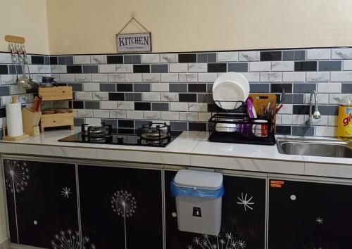 金宝Teratak Hannani Maryam Kampar ( Muslim Homestay)的厨房柜台设有水槽和炉灶。