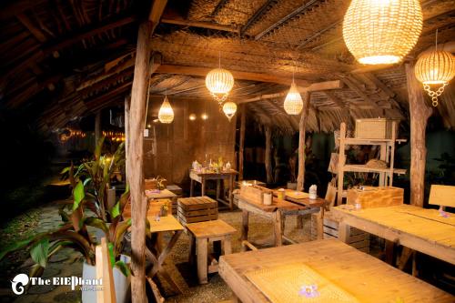 达瓦拉维The Elephant Next-Door的餐厅设有木桌和吊灯。