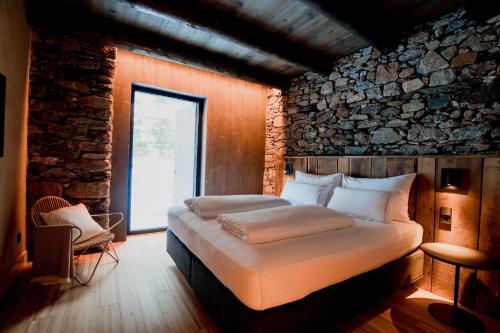 恩坎普Les Pardines 1819 Mountain suites & SPA的石墙客房的两张床