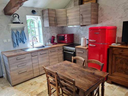 Saint-Germain-des-FossésPETIT GÎTE 18 ème tout confort的厨房配有红色冰箱和木桌