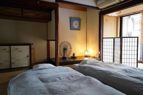 しぼり染めが体験できる古民家宿MADO的卧室配有两张床,墙上配有风扇