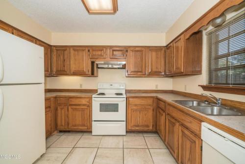 长滩Oakhaven的厨房配有木制橱柜和白色炉灶烤箱。