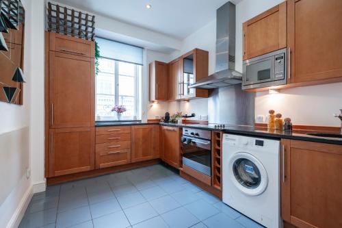 伦敦Welcome London - Trafalgar Square的厨房配有木制橱柜、洗衣机和烘干机