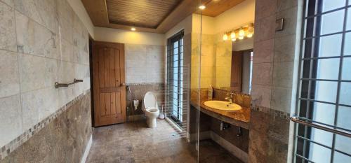 布尔班Haven Lodge Bhurban, 6BR Holiday Home in Hill Station的一间带卫生间、水槽和镜子的浴室