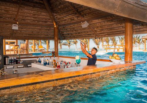 特赖里The Coral Beach Resort by Atlantica的站在水中酒吧的人