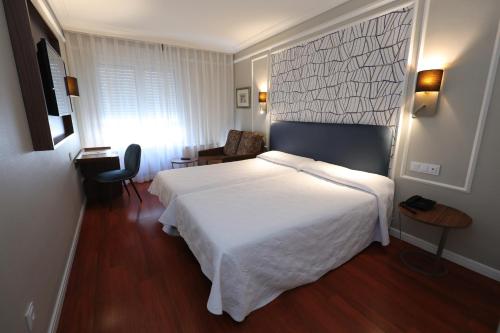 布尔戈斯Hotel Corona de Castilla Burgos的卧室配有一张白色大床和一张书桌