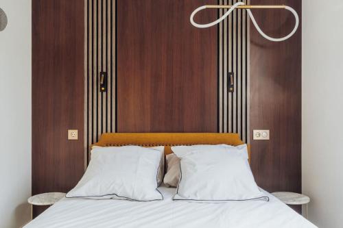 布西圣乔治Luxueux Appartement proche Disneyland的一张带白色枕头和木墙的床