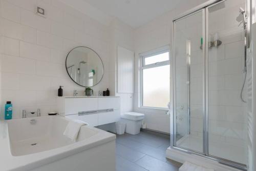卡菲利82 Van Road的白色的浴室设有浴缸和淋浴。