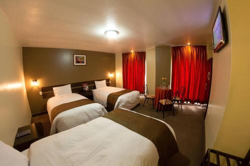 普诺UTASA VILLAREAL Inn的酒店客房,设有三张床和红色窗帘