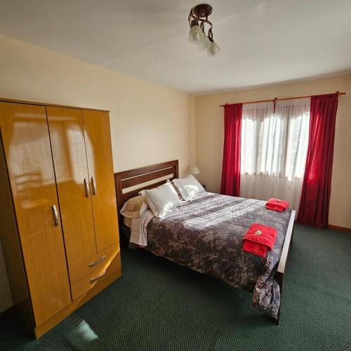 乌斯怀亚Casa de familia的一间卧室配有床和带红色窗帘的橱柜