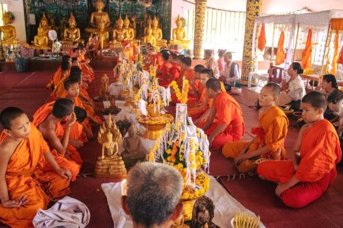 万象DaViKa Hotel的一群身着橙色长袍的人坐在寺庙里