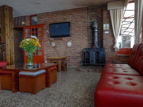 阿基塔尼亚Hotel Refugio Santa Ines的客厅设有红色的沙发和壁炉
