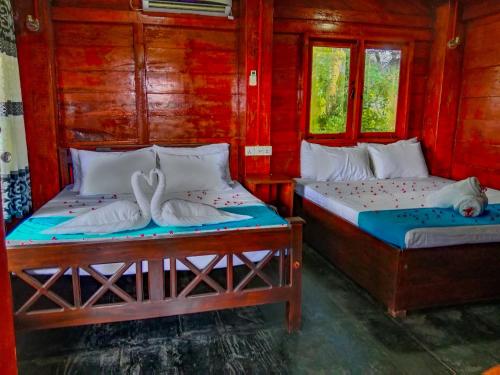锡吉里亚Ceylon Amigos Eco Resort的宿舍间的两张床,设有红色的墙壁和窗户