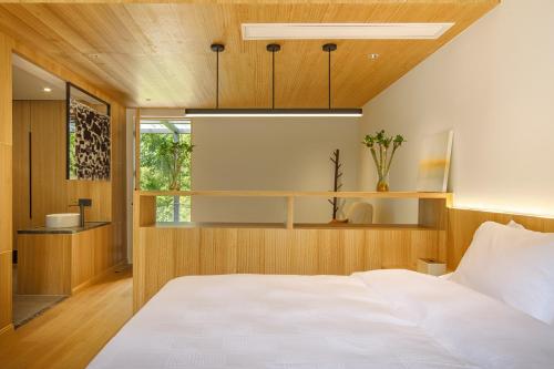 德清La Petronilla Boutique Hotel Moganshan的卧室设有白色的床和木制天花板。