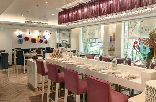 新德里阿斯坦萨诺瓦门廊酒店的餐厅设有长桌和红色椅子