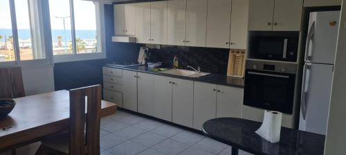 海法Светлая и уютная квартира у моря的厨房配有白色橱柜、水槽和冰箱。
