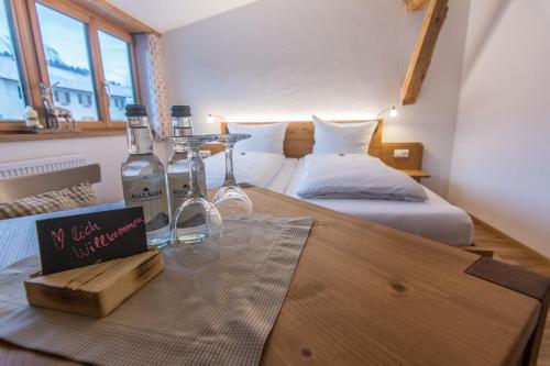 雷滕贝格Gasthof Hirsch Vorderburg的一间客房配有两张床和一张桌子,并提供两瓶葡萄酒