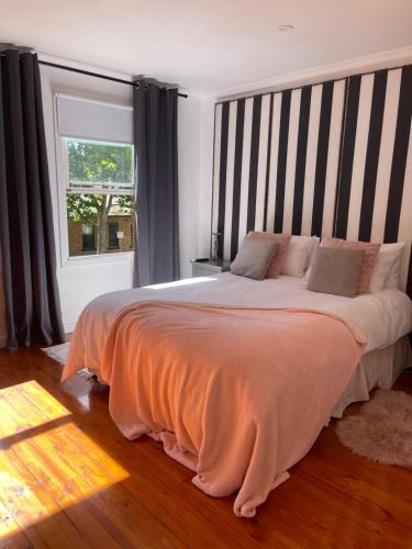 墨尔本Luxury Fitzroy House的一间卧室配有一张带条纹床头板的大床