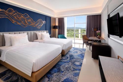美娜多The Sentra Manado的酒店客房设有两张床和电视。