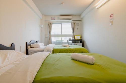 福冈Fukuoka Share Hotel的一间带三张床的卧室,配有绿色和白色