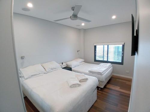 悉尼Brand NEW VIP Luxury 5/5 Star Beachside Escape的配有2张床的白色墙壁和窗户。