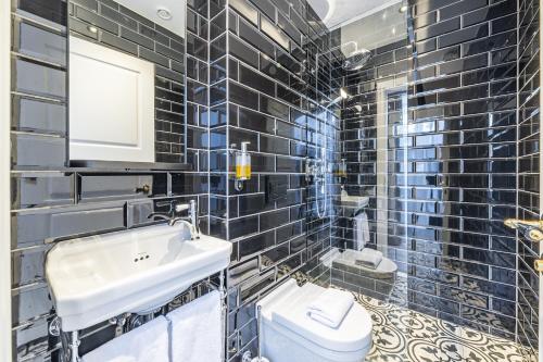 雷克雅未克Hotel Aska的黑色瓷砖浴室设有水槽和卫生间