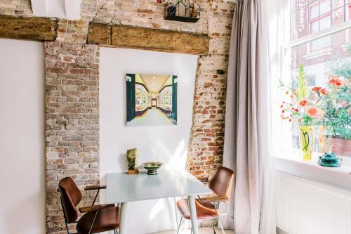 多德雷赫特B&B À la Lon的一间设有白色桌椅和砖墙的房间