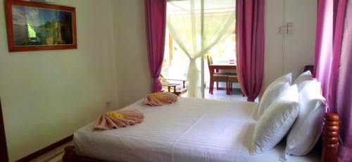 拉迪格岛Dan Zoranz Self Catering Guest House的卧室配有一张白色大床和粉红色窗帘