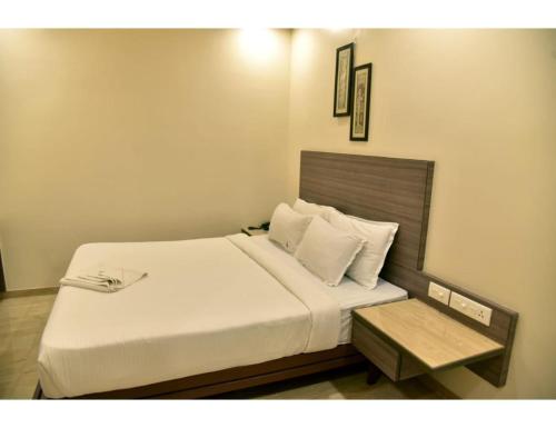 那格浦尔Hotel Dwarka, Nagpur的卧室配有一张白色的床和一张桌子