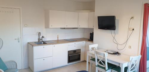 赞德沃特扎德沃特安兹膳食公寓的厨房配有白色橱柜、桌子和电视。