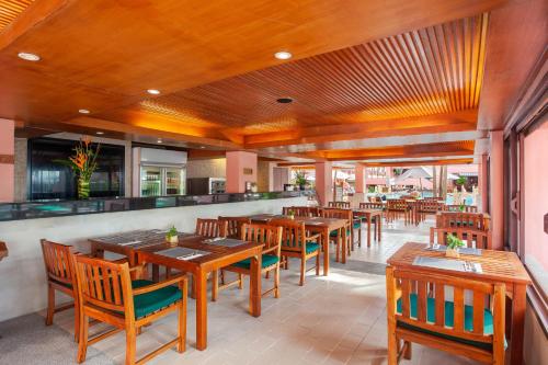 芭东海滩普吉岛-瓶庐海景度假酒店 Phuket PL Seaview Resort的一间空餐厅,配有木桌和椅子