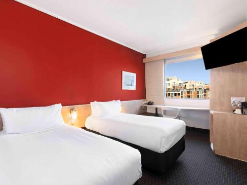 悉尼悉尼达令港宜必思酒店的酒店客房设有两张床和红色的墙壁。