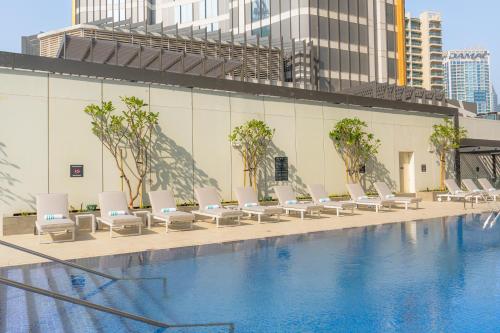 迪拜Holiday Inn Dubai Business Bay, an IHG Hotel的一座带白色躺椅的游泳池,位于大楼旁