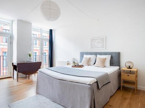 哥本哈根Sanders Leaves - Chic Three-Bedroom Apartment In Downtown Copenhagen的白色卧室配有一张大床和一张书桌