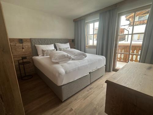 萨姆瑙恩Samnaun, ChaletdMot的卧室配有带枕头的床铺和窗户。