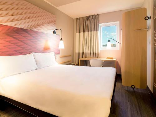 埃雷欣ibis Erechim的酒店客房设有白色的床和窗户。