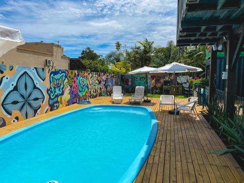 普腊亚罗萨Innbox - Praia do Rosa的一个带椅子的游泳池以及一堵涂鸦墙