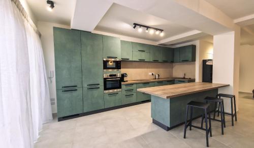 休吉让Mgarr ix-Xini Holiday apartment的厨房配有绿色橱柜和带凳子的台面
